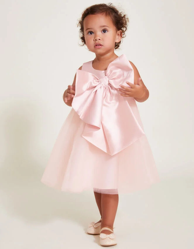 a pink dress with a large bow 